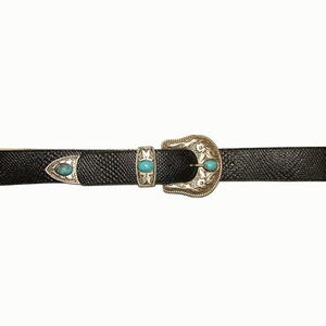 May include: Black belt with a textured pattern, featuring a silver-colored buckle and accents. The buckle has a decorative design and is adorned with turquoise-colored stones. The belt is a stylish accessory.