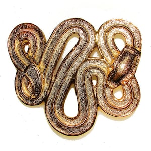 May include: A gold-toned metal belt buckle shaped like a snake. The buckle is intricately detailed with a textured surface.