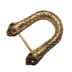 May include: A gold-colored belt buckle in the shape of a snake. The buckle features a detailed design with a textured pattern and two snake heads at each end. The buckle is approximately 3 inches long.