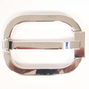 May include: Silver metal belt buckle with a rectangular shape and a smooth, polished finish.