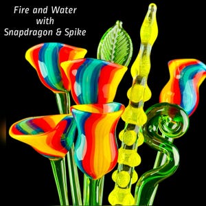 May include: A collection of glass sculptures featuring multi-colored flowers with red, yellow, and blue stripes, a green leaf, a yellow textured spike, and a green spiral stem. The text "Fire and Water with Snapdragon & Spike" is visible.
