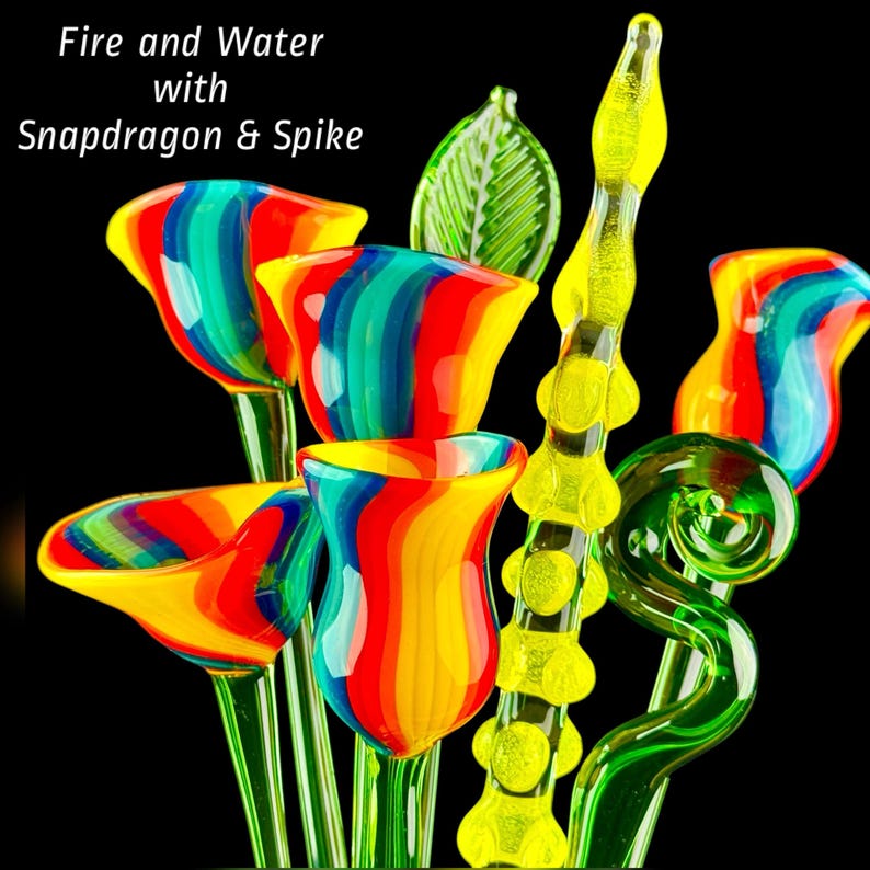 May include: A collection of glass sculptures featuring multi-colored flowers with red, yellow, and blue stripes, a green leaf, a yellow textured spike, and a green spiral stem. The text "Fire and Water with Snapdragon & Spike" is visible.