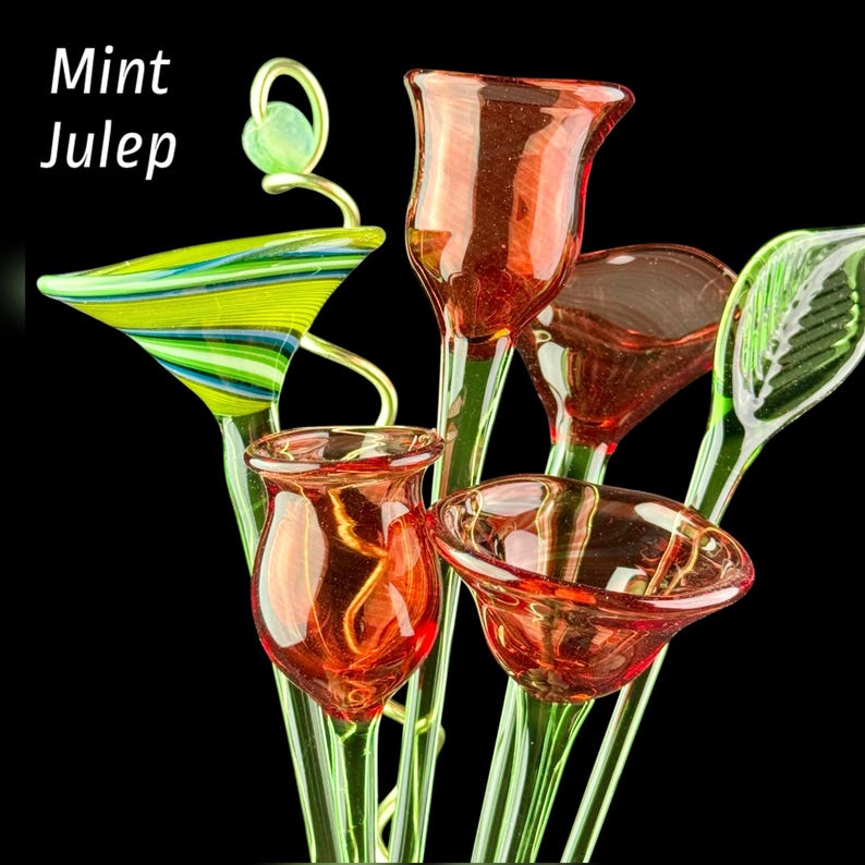 May include: A collection of glass flower sculptures featuring red tulip-shaped blossoms, a green and blue striped funnel-shaped piece, and a green leaf-shaped element. The text Mint Julep is visible in the upper left corner against a black background.