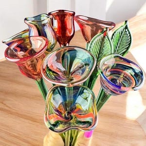 May include: A collection of handcrafted glass flowers featuring vibrant, multi-colored petals in shades of red, orange, blue, and green. The bouquet includes several trumpet-shaped blossoms with swirling patterns and two distinct green glass leaves.