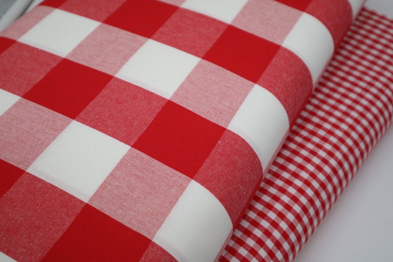 May include: Two red and white gingham fabrics, one with larger squares than the other.