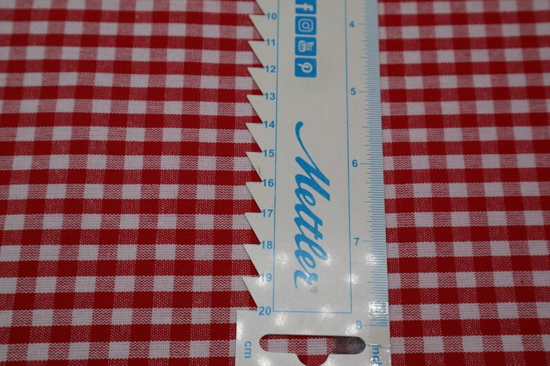 May include: A white and red gingham fabric with a ruler measuring 20 centimeters. The ruler is labeled "Mettler" and has markings in centimeters and inches.