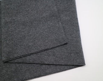 May include: A dark charcoal gray fabric featuring a fine vertical ribbed texture. The material is folded over itself, displaying a consistent knit pattern across the surface with a matte finish and a clean, straight edge along the fold line.