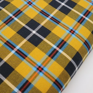 May include: Yellow, blue, red and black plaid fabric with a woven texture.