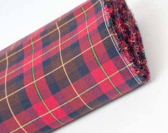 May include: Rolled fabric with a classic plaid pattern. The fabric features a red base with intersecting lines in brown, navy, and yellow. The edge of the roll shows the frayed, unfinished edge of the fabric. The fabric is likely used for apparel or home decor.
