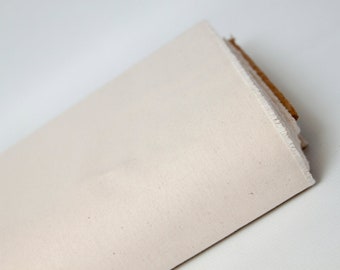 May include: A roll of off-white canvas fabric with a raw edge. The fabric is folded and rolled up, with a brown cardboard core visible.