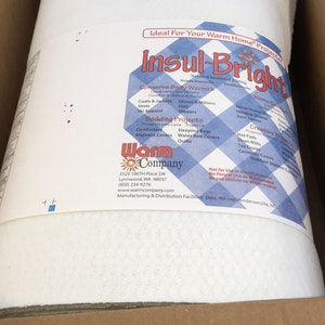 May include: A roll of white Insul-Bright needled insulated lining inside a cardboard box. The product label features a blue and white checkered pattern, the text Insul-Bright, The Warm Company, and lists various project uses and contact details.