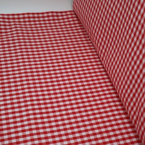 May include: Red and white gingham fabric with a small check pattern. The fabric is folded in half and the edges are visible.