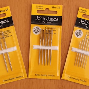 Puede incluir: Tres paquetes de agujas de chenilla John James en tamaños 14, 16 y 18/24. Cada paquete es amarillo con texto negro y presenta un logotipo de dragón. Las agujas son plateadas y están empaquetadas en una manga de plástico transparente.