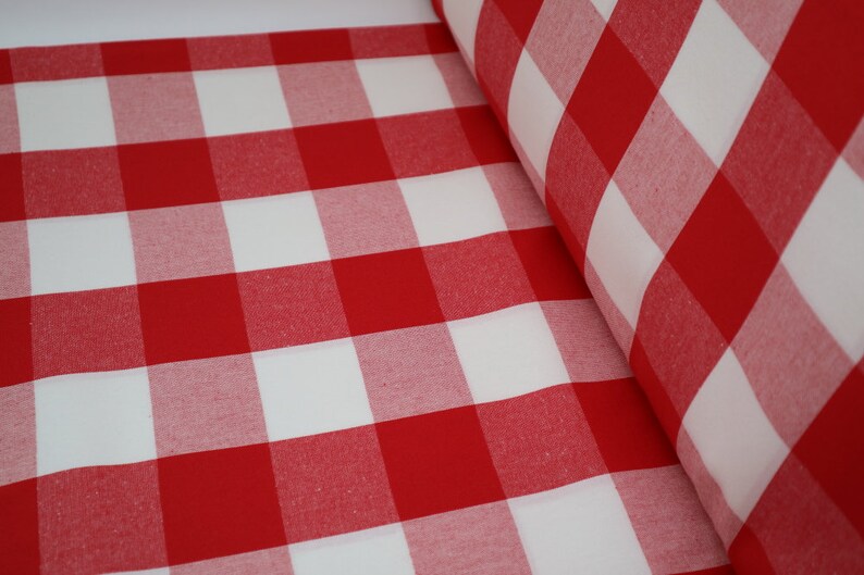 May include: Red and white checkered fabric with a large square pattern. The fabric is folded and rolled up.