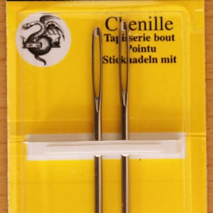 May include: Two silver-coloured John James size 14 chenille needles packaged in a yellow and black card. The packaging features the text 2 Needles, JJ18814, Size 14, John James, Est. 1840, Chenille, Tapisserie bout Pointu, Sticknadeln mit, and Finest Quality Needles.