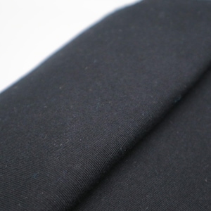 May include: A solid black fabric with a visible woven texture, featuring a distinct fold that creates a diagonal line across the surface. The material appears matte and opaque, showing a consistent dark color throughout the entire visible area.