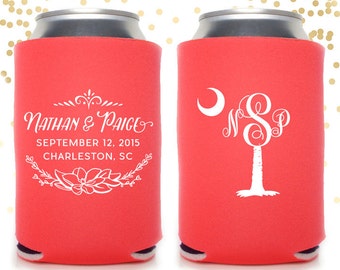 May include: Two coral pink can coolers with white text and designs. One cooler has the text "Nathan & Paige" with the date "September 12, 2015" and "Charleston, SC". The other cooler has a palm tree with a crescent moon and the monogram "NSP".