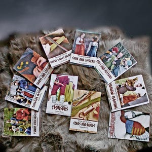 May include: A collection of books on Viking Age clothing, featuring titles like "Tunics and Dresses," "Sark and Smokkr," and "Caps and Mittens." The books are displayed on a textured, fur-like surface.