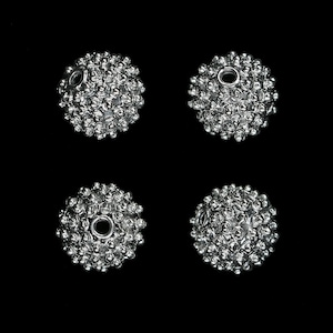 May include: Four silver metal beads with a textured surface and a hole in the centre. The beads are round and have a spiky appearance.
