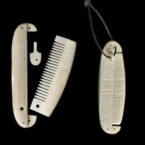 May include: A white ivory folding comb with intricate carved designs. The comb is closed and has a small loop at the top for hanging.