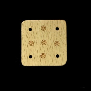 Può includere: Un quadrato di legno marrone chiaro con nove fori equidistanti. I fori sono disposti in uno schema a griglia 3x3.