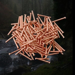 Könnte beinhalten: Ein großer Haufen kupferfarbener Metallnadeln. Die Nadeln sind alle gleich groß und gleich geformt und in einem zufälligen Muster angeordnet. Die Nadeln sind glänzend und haben einen metallischen Glanz.