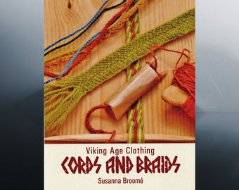 May include: A book titled "Viking Age Clothing: Cords and Braids" by Susanna Broomé. The cover features a wooden background with colorful cords and braids, a wooden spool of red thread, and a wooden tool.