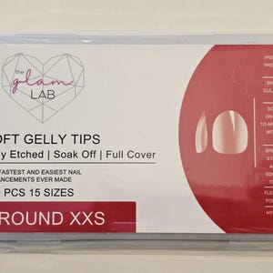 May include: A rectangular package of soft gel nail tips from The Glam Lab. The package has a white background with red accents and includes the text "SOFT GELLY TIPS" and "ROUND XXS". The package contains 150 pieces in 15 sizes.