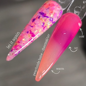 May include: Two long, pointed artificial nails. One is a mix of pink, purple, and gold glitter with the text "lei it again." The other is a thermal/UV nail that changes from pink to peach with temperature changes, labeled "peachside babe - thermal/uv."
