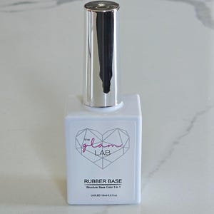 May include: A white rectangular nail polish bottle with a silver cap. The bottle has the text "the glam LAB" in a heart-shaped design, and "RUBBER BASE" with "Structure Base Color 3 in 1" and "UV/LED 15ml-0.5 fl oz" below.