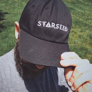 May include: A black baseball cap with a white embroidered logo that says "STARSEED".