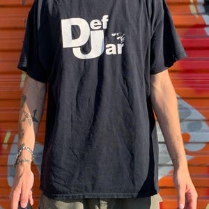May include: Black t-shirt with a white "Def Jam" logo and a small graphic of a microphone.
