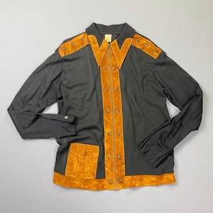 May include: A black long-sleeved shirt with a brown suede collar, front panel, and pocket. The shirt has a zip closure and decorative metal studs.