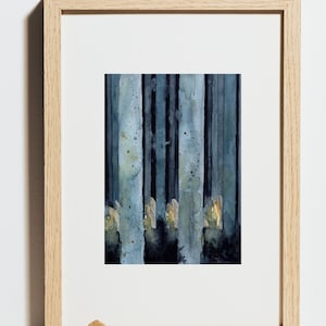 May include: A framed watercolor painting of a forest scene. The artwork features vertical strokes of blue and black, suggesting tree trunks. Hints of gold and yellow add highlights. The frame is made of light-colored wood.