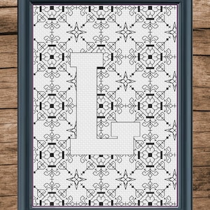 May include: Black and white cross-stitch pattern with a large letter L in the center. The pattern is framed in a black frame.