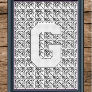 May include: A black and white framed cross-stitch design featuring the letter "G" in a white font against a background of a repeating geometric pattern.