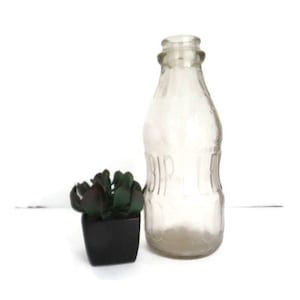 May include: A clear glass bottle with a textured surface and the word "Bar-I-T" embossed on the side. The bottle is empty and has a slightly rounded shape.