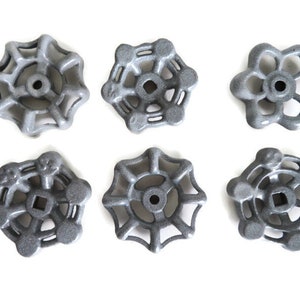 May include: Six gray metal faucet handles with various spoke designs are arranged on a white background. Each handle has a central hole and a unique spoke pattern, showcasing a range of industrial hardware designs.
