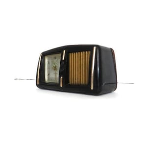 May include: A black vintage clock radio with a gold speaker grille and a white clock face.
