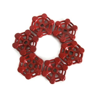 May include: Six red metal valve handles with a starburst design. The handles are arranged in a circle.