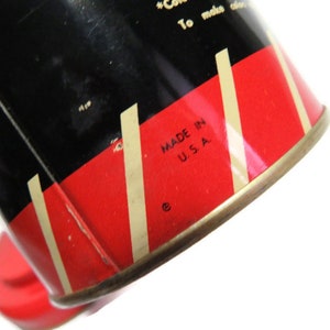 May include: Close-up of a red and white striped tin can with black lettering. The text reads "Made in U.S.A.".