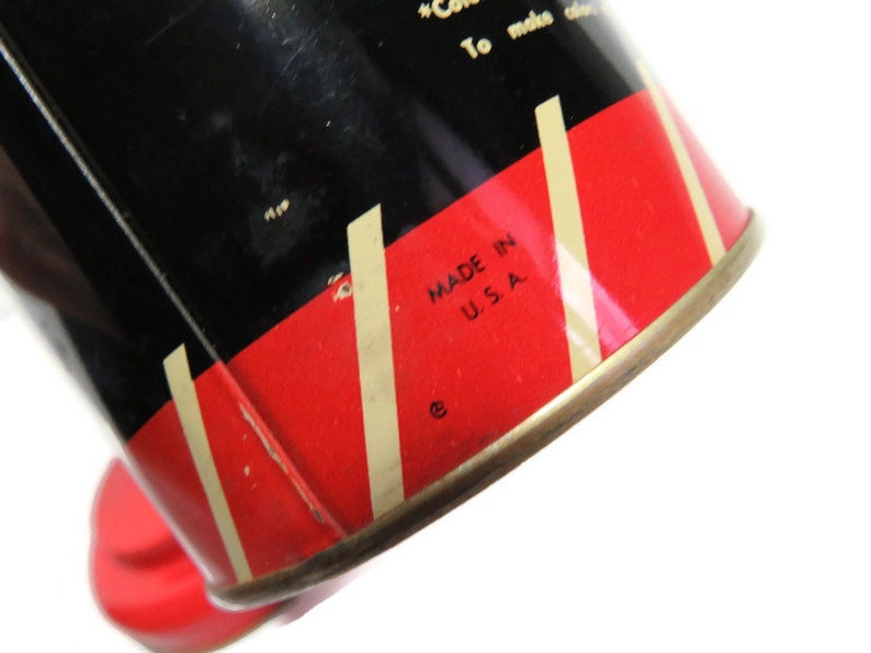 May include: Close-up of a red and white striped tin can with black lettering. The text reads "Made in U.S.A.".
