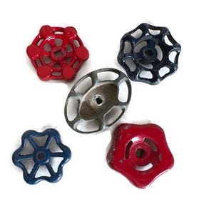 May include: Five vintage valve handles in red, blue, and silver. The handles have various star and oval shapes, with a central hole for attachment. The handles are made of metal and appear to be aged.
