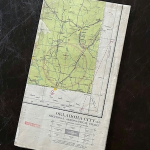 May include: A vintage, tan-colored, paper aeronautical chart for Oklahoma City (R-5). The chart is titled "Sectional Aeronautical Chart" and includes a map of the area with roads, rivers, and other geographical features. The chart is marked "Restricted" in red.