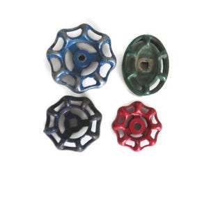 May include: Four vintage metal water valve handles in different colors. The handles are round with a starburst design and have a hole in the center. The colors are blue, green, red, and black.