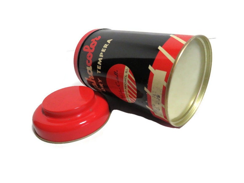May include: A red and black paint can with the text "Ja-color Dry Tempera" and "Made in U.S.A." The can has a red lid.