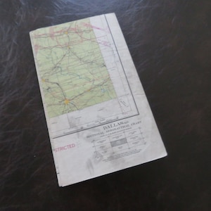 May include: A vintage aeronautical chart for the Dallas area. The chart is printed on paper and has a green and brown color scheme. The chart is labeled "Dallas Sectional Aeronautical Chart".