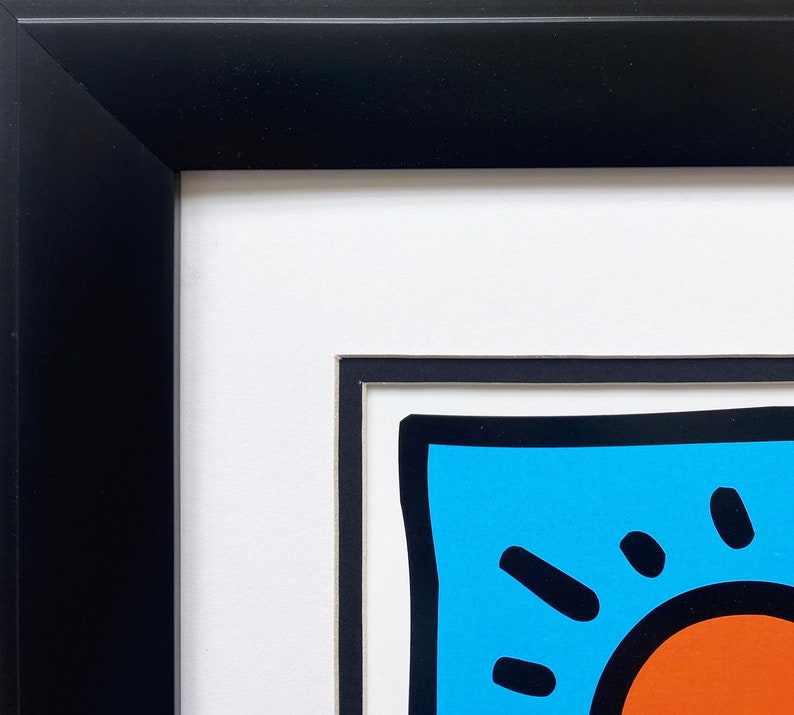 Puede incluir: Primer plano de una obra de arte enmarcada que presenta un dise&ntilde;o abstracto colorido con un fondo azul, un contorno negro y un c&iacute;rculo rojo en el centro.