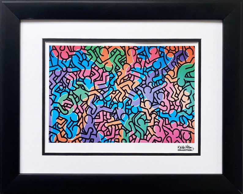 Op de afbeelding: Een ingelijste print met een levendig kunstwerk met een herhalend patroon van gestileerde figuren in verschillende kleuren, waaronder blauw, groen, oranje en roze. Het kunstwerk is ingelijst in een zwart frame met een witte passe-partout. De print is gelabeld "Keith Haring Collection."