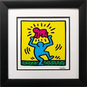 May include: A blue figure with a pink figure on its head, both figures are stylized and simple, the background is yellow with green grass at the bottom, the artist's signature "Keith Haring" is in the bottom right corner.